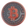Gros plan d'un dessous de verre Bitcoin - logo BTC orange en relief sur fond noir