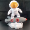 Statuette astronaute Bitcoin vue de face - visière dorée au logo BTC, chevauchant une fusée grise
