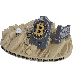 Statuette Bitcoin ne meurt jamais vue de face - pierre tombale gravée au logo Bitcoin sur socle désert